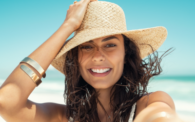 happy woman after invisalign wearing straw hat in summer beach e1679326058140
